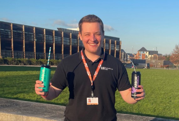 Photo of Matt Hollis holding two cans of beer with different types of straws